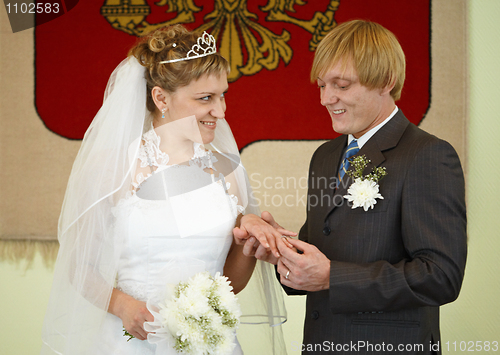 Image of Happy newlyweds wear wedding ring