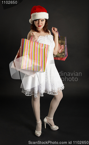 Image of Beautiful girl in Christmas cap with gifts in hands