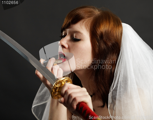 Image of Bride lipstick using reflection in sword