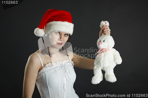 Image of Woman in Christmas cap holds in hand a white rabbit