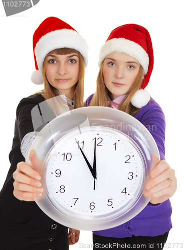 Image of Two girls in New Year's caps with clock