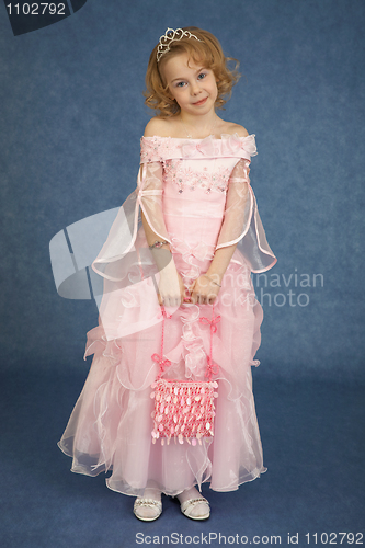 Image of Little girl in pink dress stands on blue background