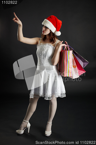 Image of Woman in New Year's cap chooses purchases and gifts