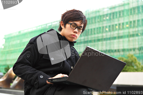 Image of asian man using computer outdoor