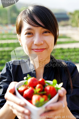 Image of smile girl give you bowl of strawberries