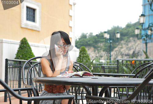 Image of girl read book and talk phone in cafe