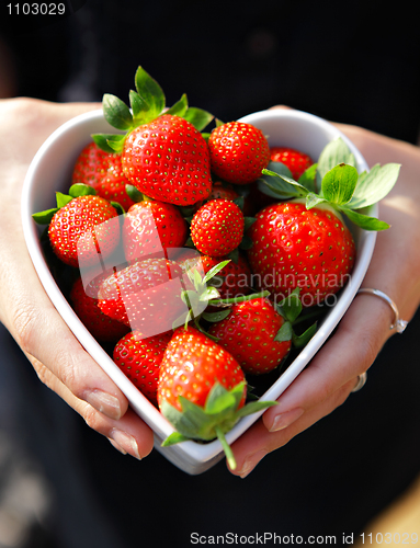 Image of strawberries in heart shape bowl with hands