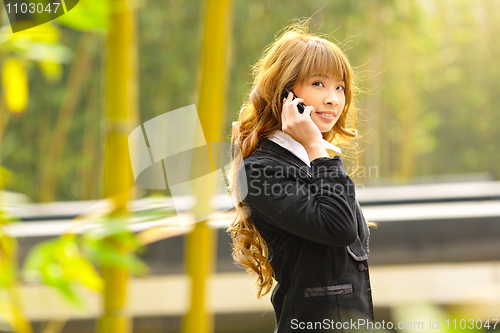 Image of businesswoman talk phone beside trees