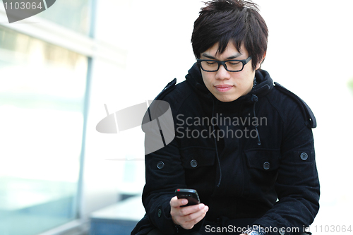 Image of casual asian man sms on cell phone