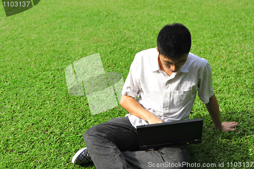 Image of asian man using computer outdoor