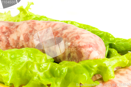 Image of Closeup of one Uncooked Sausage on salad leaf