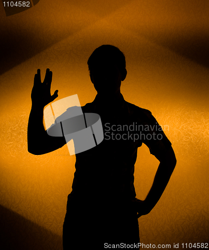 Image of Back lit silhouette of man with raised hand