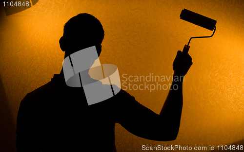 Image of Back lit silhouette of man with paint-roller