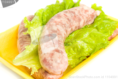 Image of Uncooked Sausage on salad leaf