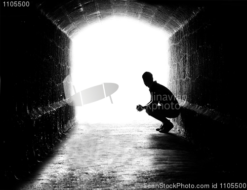 Image of Human sitting silhouette in back-lit in tunnel exit