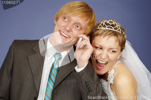 Image of Happy bride and groom is congratulated by phone