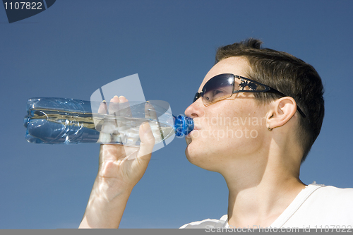 Image of The girl a unisex drinks water from a bottle