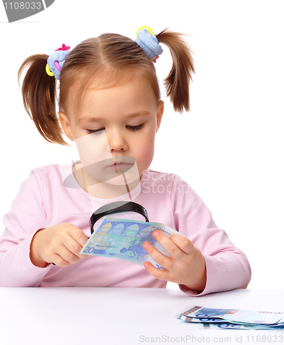 Image of Girl is looking at euro banknote using magnifier