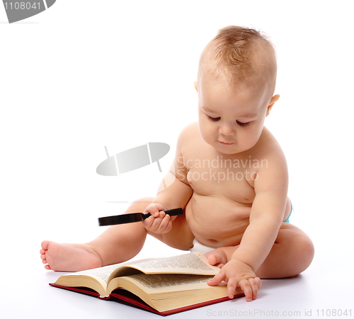 Image of Little child play with book and magnifier