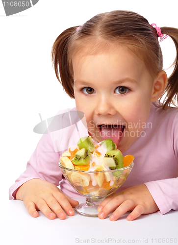 Image of Little girl licks fruit salad