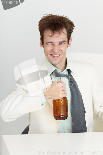 Image of Cheerful guy in a white jacket with bottle of beer