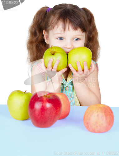 Image of Girl playing with ripe apples sitting at table