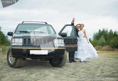 Image of Happy newly-married couple says goodbye near car