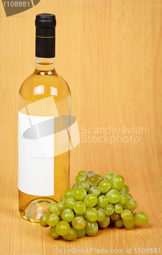 Image of Still life - bottle of white wine and grapes on wooden surface