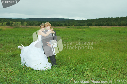 Image of Bride and groom embrace on field