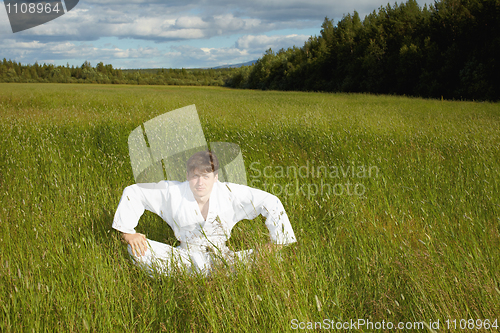 Image of Young man sits in a grass