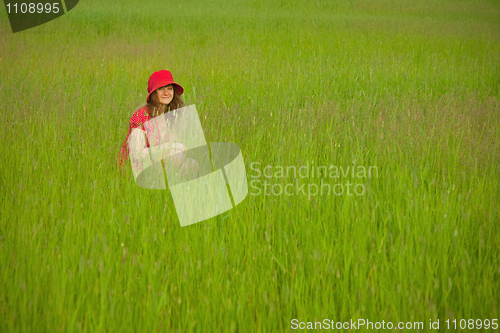 Image of Woman in red clothes sits in green grass