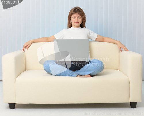 Image of Beautiful girl looking movie sitting on couch with laptop