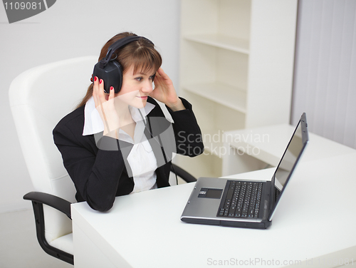 Image of Woman listens to music by means of laptop and ear-phones