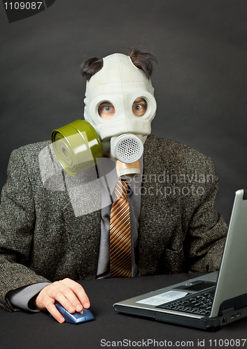 Image of Amusing person has dressed gas mask and works with computer