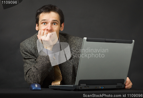 Image of Surprised person with computer. Sits and thinks.