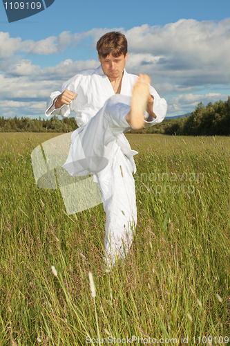 Image of Young man in white kimono trains to beat foot