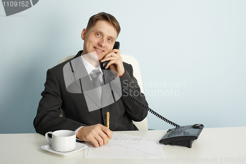 Image of Smiling businessman in talks on phone