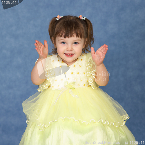 Image of Little girl in beautiful dress claps his hands