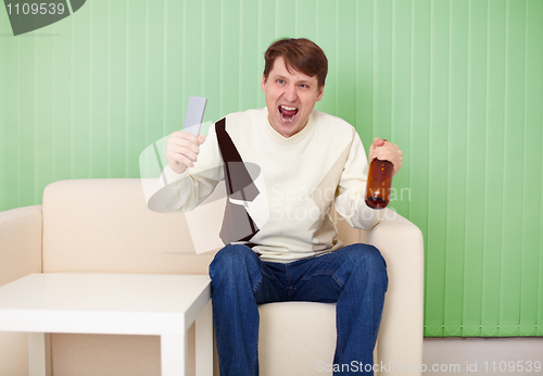 Image of Football fan sitting at home on couch with TV