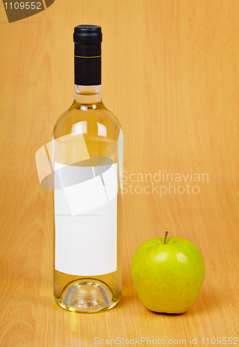 Image of Bottle of cider and apple on table