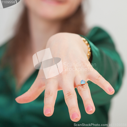 Image of Woman shows new ring with blue gem