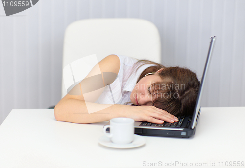 Image of Woman tired and fell asleep at table with a laptop