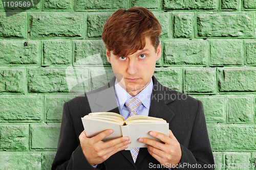 Image of Person reads book on background of green wall