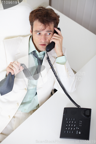 Image of Young businessman talking on phone very excited