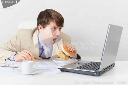 Image of Comic clerk eats sandwich looking at screen