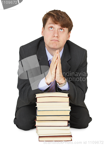 Image of Student prays before examination on pile of textbooks