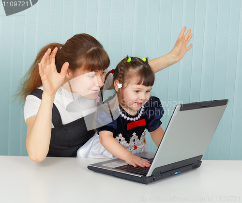 Image of Girl and mother are playing with laptop