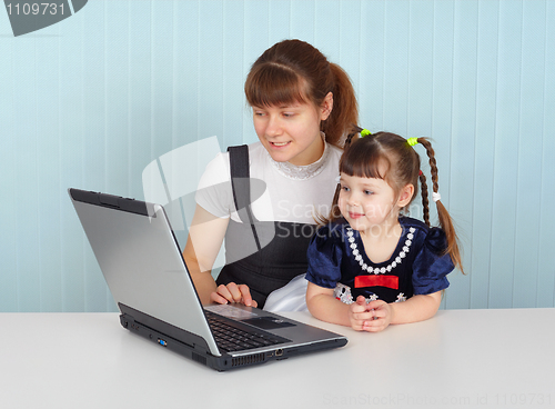 Image of Woman and child sitting at table with laptop