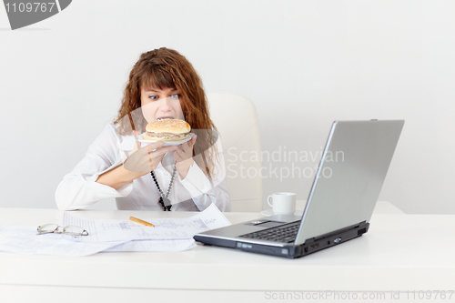 Image of Young girl has hastily dinner sandwich at office