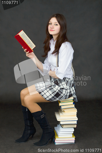 Image of Girl - student sitting on pile of textbooks